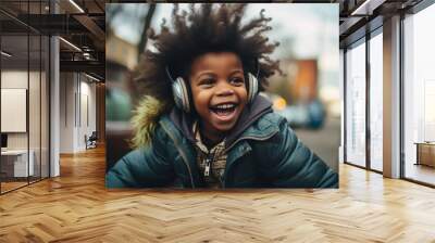 Portrait of a happy young black boy smiling thrilled, with big curly hair outdoors in a street wearing a jacket and a headset, intense expression playful smile joy afro american child african american Wall mural