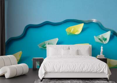 Colorful paper ships in blue water. Conceptual setting. Minimalistic art. Pastel background. Wall mural