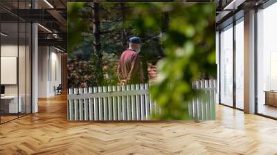 an elderly man walks with a mask on his face at the time of infection kovid 19 Wall mural