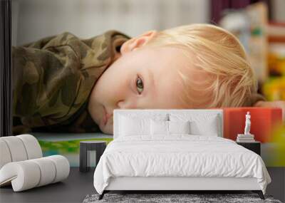 Little boy with blond hair lies sad on the floor Wall mural