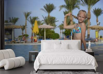 Teenage blonde girl sit in pool and smile Wall mural