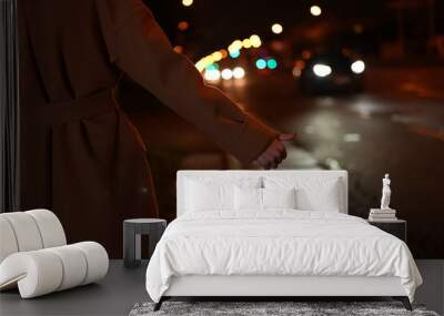 woman raise her hand to stop the car on the night road Wall mural