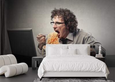 man eating a huge dish of pasta in front of her laptop Wall mural