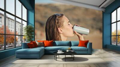 young woman at the beach drinks from a can Wall mural