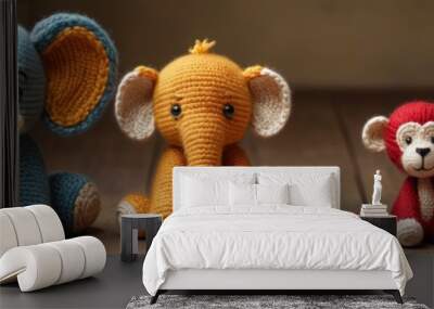 A photo of four crocheted stuffed animals - two elephants and two monkeys - sitting side by side on a wooden floor. Wall mural