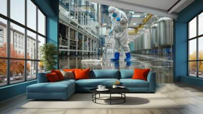 Worker in protective gear cleaning industrial floor with mop in modern factory. Hygienic procedures in a large production facility. Sanitation team at work ensuring cleanliness. Industrial cleaning Wall mural