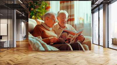 Elderly man and woman sitting on the sofa and watching a magazine Wall mural