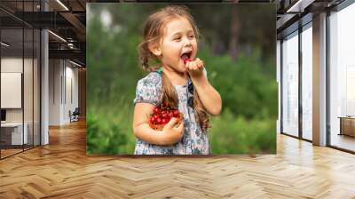 little girl eating cherries from a basket on nature Wall mural