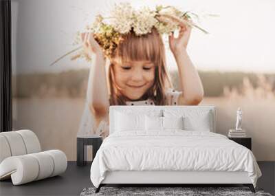 Little pretty girl in a wreath of flowers on her head in nature in the summer Wall mural