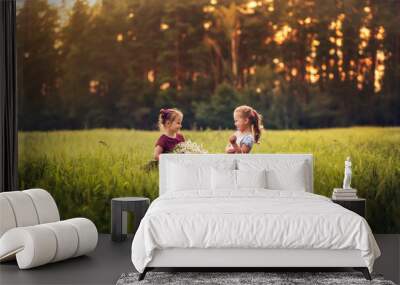 two little girls with a big bunch of chamomiles on a meadow
 Wall mural