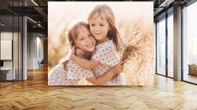 Two little happy identical twin girls playing together in nature in summer. Girls friendship and youth concept. Active children's lifestyle. Wall mural