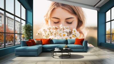 Young beautiful girl with a bouquet of daisies in a wheat field Wall mural