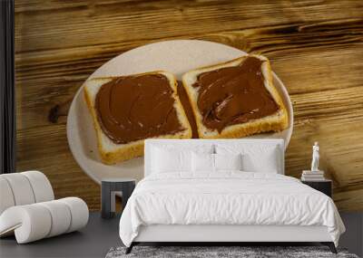 Two slices of bread with delicious chocolate hazelnut spread on wooden table Wall mural