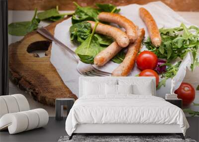 Grilled sausages with cherry tomatoes ,spinach and arugula on a wooden background in rustic style Wall mural