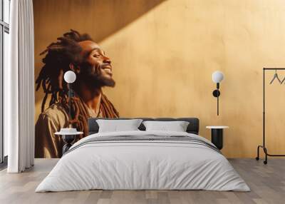 African man with dreadlocks standing over yellow wall looking up to sunlight and smiling, with copy space Wall mural