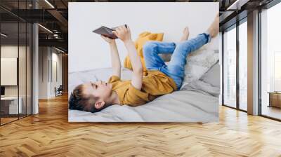 Toddler boy playing with digital wireless tablet computer at home. Baby child growing with online applications. Child and electronic devices concept. Portrait of toddler with smartphone Wall mural