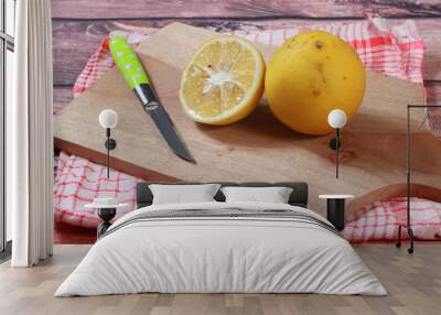 Top View Close Up two Lemon and stainless steel sharp knife at wooden cutting board Wall mural