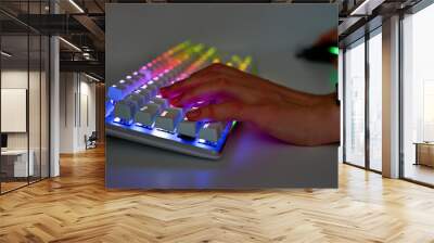 Colorful keyboard with RGB light and hand, blurred background. The player's hands on the keyboard and mouse, close-up. The concept of esports and gaming Wall mural