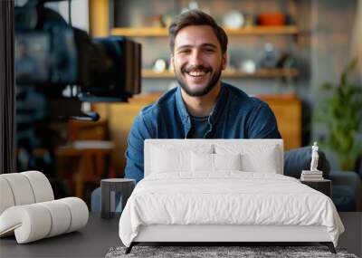 Smiling Man Being Interviewed on Camera. Cheerful man in a casual shirt sitting for an on-camera interview in a cozy room, giving a sense of approachability and openness. Wall mural