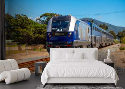 Passenger train with diesel engine and coaches arriving in Carpinteria, California (USA). Scenic railway public transport heading north between Los Angeles and San Francisco on the Pacific Coast.  Wall mural