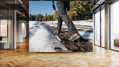 Trekking or hiking on a wet trail. Close up shot of hiking boots or shoes. Outdoor path with snow and water. Detail photo of outdoor hiking boots. Wall mural