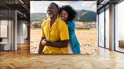 Beautiful mature black couple of lovers dating at the seaside - Married african middle-aged couple bonding and having fun outdoors, concepts about relationship, lifestyle and quality of life Wall mural