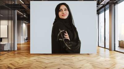 Beautiful woman from Dubai posing on colored background with traditional abaya. Wall mural