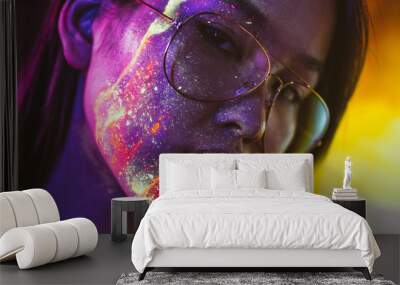 Beautiful young woman dancing and making party with fluorescent painting on her face. Neon facial portraits Wall mural