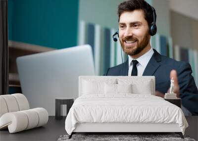 Businessman sitting at computer desk in the office with microphone headset Wall mural