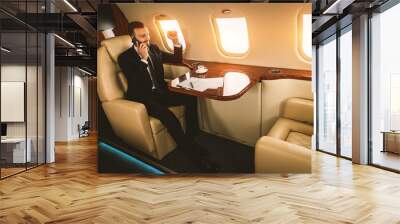 Businessman wearing corporate business suit flying on luxury private jet, concepts about travel, transportation and wealthy lifestyle Wall mural