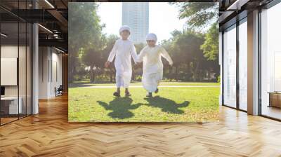 Children playing together in Dubai in the park. Group of kids wearing traditional kandura white dress from arab emirates Wall mural