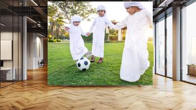 Children playing together in Dubai in the park. Group of kids wearing traditional kandura white dress from arab emirates Wall mural