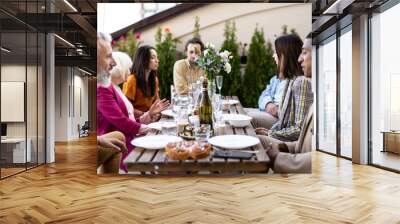 Family and friends celebrating at dinner on a rooftop terrace Wall mural