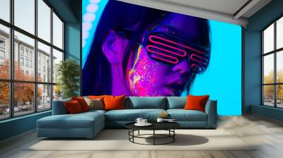 Fashion model with fluo painting on the face - Creative fashion portrait of young beautiful asian woman with fluorescent make-up, futuristic and metaverse concept Wall mural