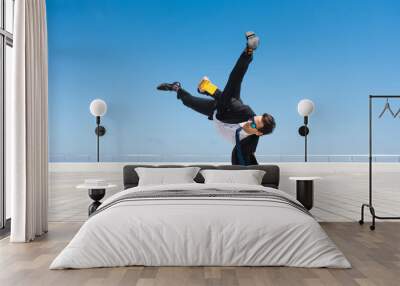 Flexible and cool businessman doing acrobatic trick Wall mural