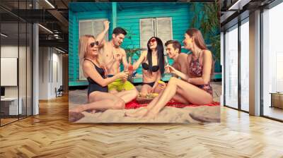 Group of five friends celebrating in their summer beach house Wall mural