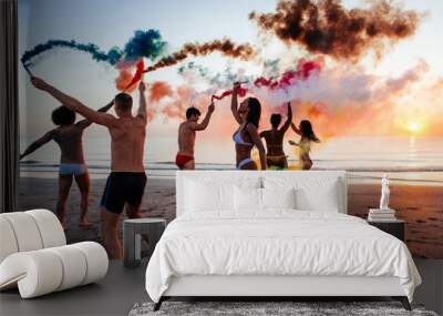 Group of friends having fun running on the beach with smoke bombs Wall mural