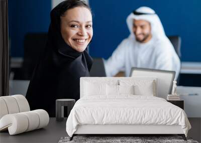 Handsome man and woman with traditional clothes working in an office of Dubai Wall mural