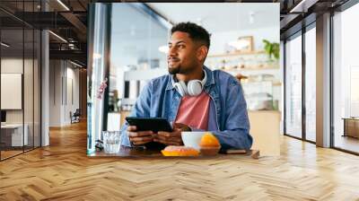 Handsome young hispanic man sitting in a bar cafeteria -  heerful african-american male relaxing in a pastry bakery coffee shop Wall mural