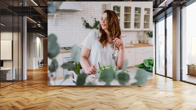 Lifestyle moments of a young woman at home. Woman preparing a salad in the kitchen Wall mural