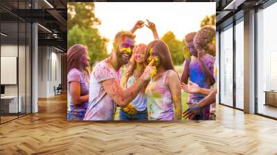 Multiethnic group of happy playful friends playing and having fun with holi colorful powder at the park Wall mural