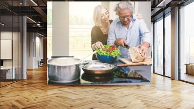 Senior couple cooking and having fun in the kitchen Wall mural