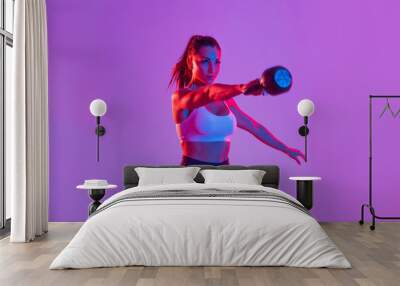 Sportive beautiful woman training with athletic body and sportswear doing workout, colorful lighting and background Wall mural