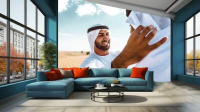 Two business men wearing traditional uae white kandura spending time in the desert of Dubai Wall mural