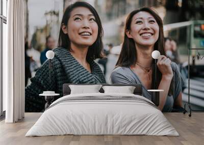 Two japanese women around in Tokyo during daytime. Making shopping and having fun Wall mural