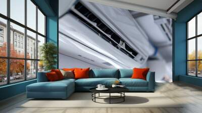 Detailed view of a modern ceiling air conditioner unit showing grilles and components in a bright interior Wall mural