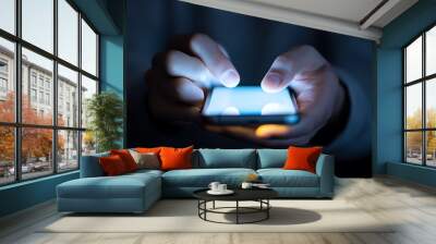 Illuminated Phone Interaction, a person focused on their smartphone screen in a dimly lit environment, fingers poised for navigation, capturing digital engagement moments. Wall mural