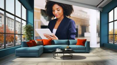 cropped shot of an attractive young businesswoman standing alone and using a tablet while in the off Wall mural