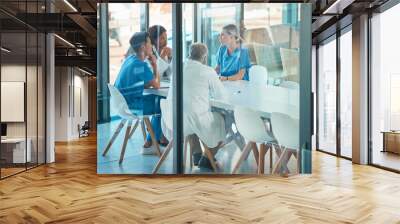 Doctors, healthcare team and meeting for a discussion, planning or training at table. Diversity men and women medical group talking about communication strategy, virus or surgery in a hospital Wall mural