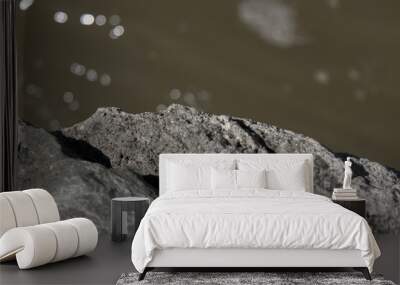 Close up of textured rocks against a high bokeh river. Wall mural